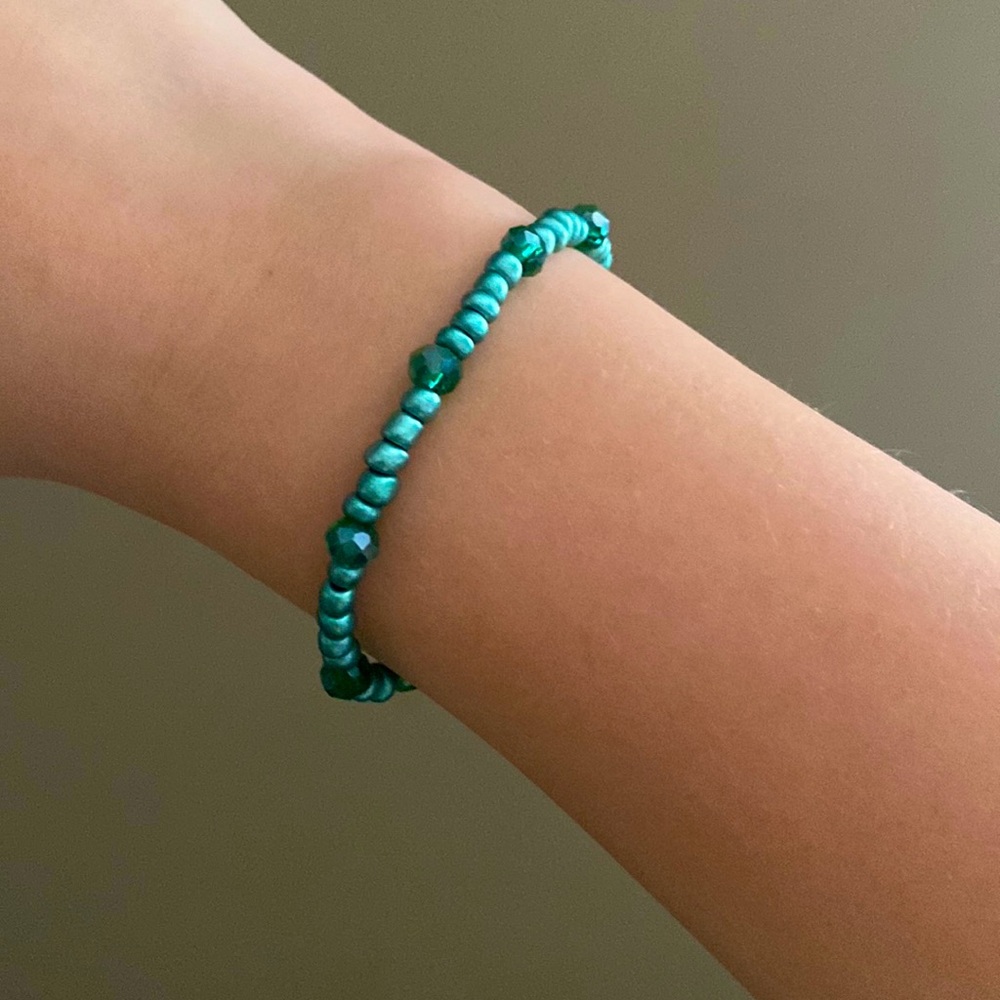 A teal bracelet with two different shades of teal beads